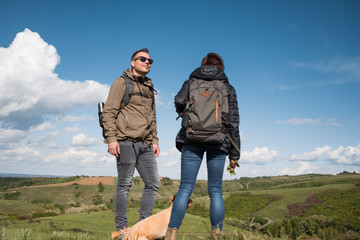 Obraz na płótnie Canvas Male and female hikers standing on the mountain top with dog