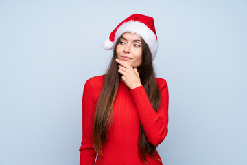 Girl with christmas hat over isolated blue background thinking an idea
