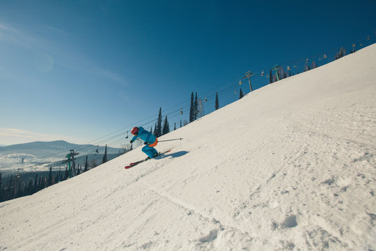 Skier skiing downhill, sunny day in high mountains