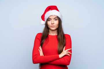 Girl with christmas hat over isolated blue background keeping arms crossed