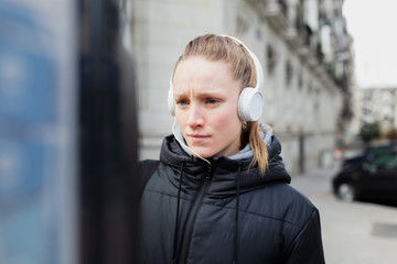 Young woman paying on parking meter in the city with jacket