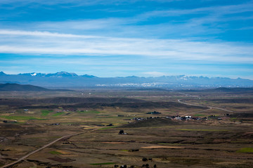 Fototapeta na wymiar Crops surrounding the dry landscape on the outskirts of La Paz with the snow capped Cordillera Real Mountain Range in the distance on a cloudy day.