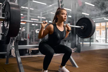 Printed roller blinds Best sellers Sport Charming strong female powerlifter dressed in black sportswear and white sneakers, doing squats, trying to stand with heavy barbell, professional sport concept, indoor shot