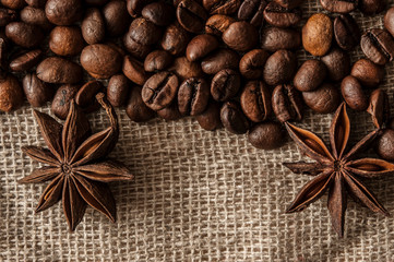 Roasted coffee beans and spice badian on a background of burlap.