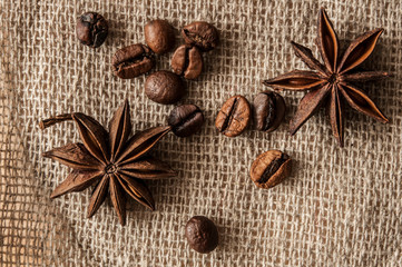 Roasted coffee beans and spice badian on a background of burlap.