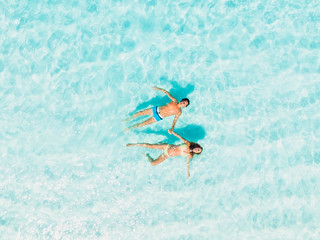 Pregnant woman with husband relaxing at tropical beach with ocean. Aerial view