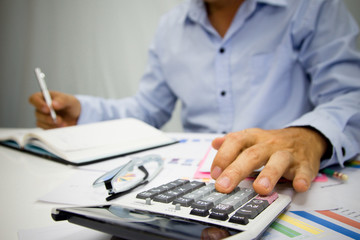 Business man using calculator and holding money for calculate tax in office.