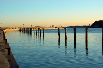 Fototapeta na wymiar Dock pillars with reflection at sun set, romantic vacation at the beach, German getaway