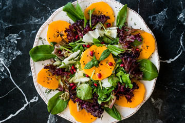 Persimmon Fruit Salad with Pomegranate, Lollo Rosso Lettuce, Rocket Arugula or Rucola and Mint Leaves.
