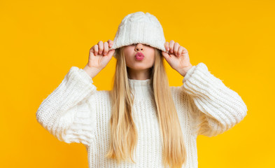 Girl with kissing lips pulling down woollen hat