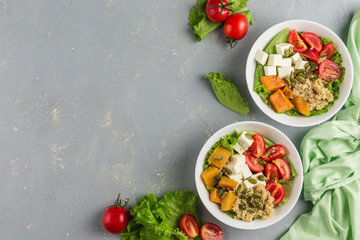 Salad bowl of quinoa, cherry tomato, baked pumpkin, pumpkin seeds, feta cheese and fresh lettuce.