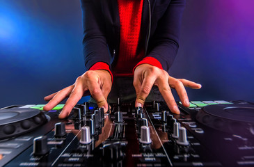Dj mixing tracks on a turntable in the night club