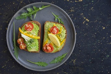 Fototapeta na wymiar sandwiches with avocado and cherry tomatoes in a plate on a dark background
