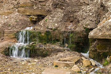 Natural textures. The spring flows from a steep rocky hillside. Early spring. Izborsk, Pskov...