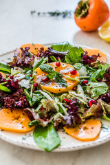 Persimmon Fruit Salad with Pomegranate, Lollo Rosso Lettuce, Rocket Arugula or Rucola and Mint Leaves.