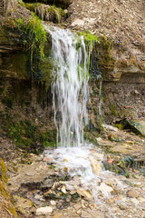 Natural textures. The spring flows from a steep rocky hillside. Early spring. Izborsk, Pskov region, Russia.