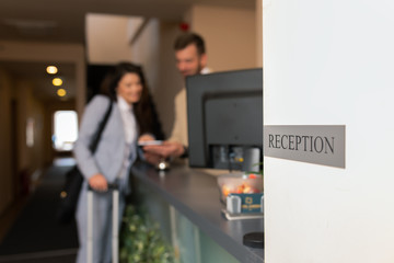 Close up of sign reception, Young businesswoman check-in in hotel, smiling male receptionist behind...