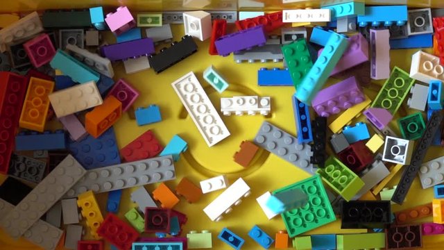 Falling colorful plastic toy bricks in box. Slow motion 240 fps, Top down view
