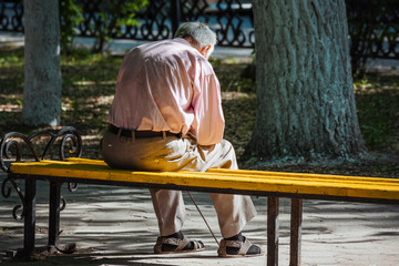 A lonely old man sitting on a bench in a park