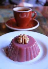Plate of Traditional Georgian Sweets Called Pelamushi with Blurry Hot Coffee in Background