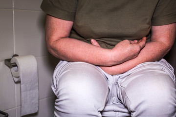 Caucasian woman is sitting on the toilet. Concept of the problem with digestion.