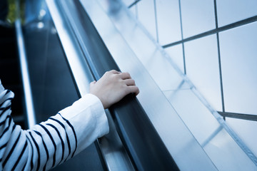 Close up image of Hand holding an escalator handrail