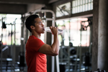 Tired fitness man drink water in gym