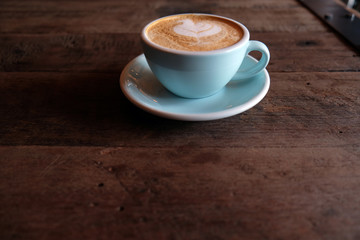 Cappuccino or latte with frothy foam, blue coffee cup top on wooden coffee shop background