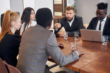 Young business partners gathered round-table to discuss main issues of their work, planning...