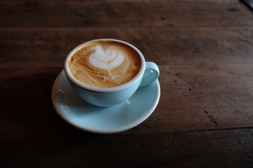 Cappuccino or latte with frothy foam, blue coffee cup top on wooden coffee shop background