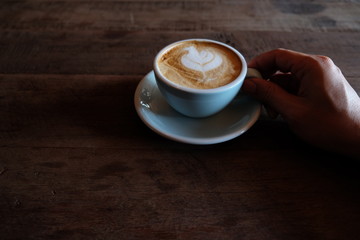 hands holding hot cup of coffee on rustic wooden table background