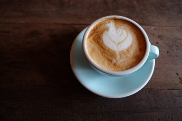 Cappuccino or latte with frothy foam, blue coffee cup top on wooden coffee shop background