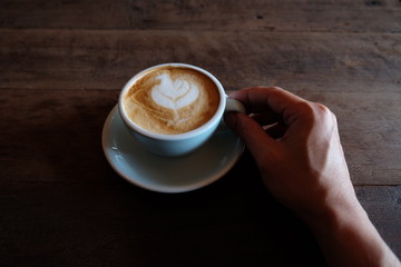 hands holding hot cup of coffee on rustic wooden table background