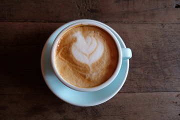 Cappuccino or latte with frothy foam, blue coffee cup top on wooden coffee shop background