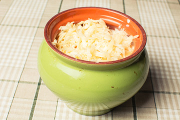 Fresh grated cheese in ceramic pot on crust baking table.
