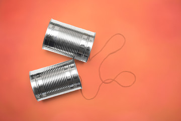 Communications and business calls concept of tin can telephone with string on orange
