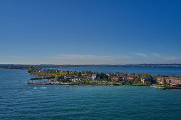 Fototapeta premium Unique view. Aerial photography, the city of Sirmione on Lake Garda north of Italy. In the background is the Alps in the snow. Resort place. Aerial view. Autumn-winter season