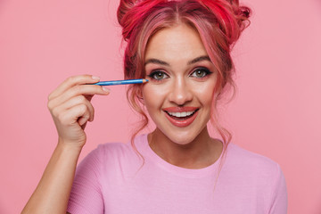 Portrait of caucasian woman laughing and applying makeup with eye pencil