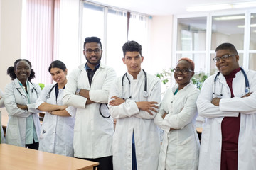 Fototapeta premium a group of doctors in the hospital corridor. Team of mixed race young men in white coats, with phonendoscopes, smiling