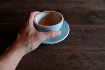 hands holding hot cup of coffee on rustic wooden table background