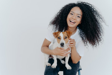 Portrait of joyful curly girl petting her dog, rejoicing buying jack russell terrier, smiles...