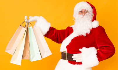 Tired Santa showing shopping bags over orange background