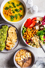 Flat lay of vegan food. Chocolate smoothie bowl, Buddha bowl with tofu, chickpeas and quinoa, lentil soup and toasts on a gray background.