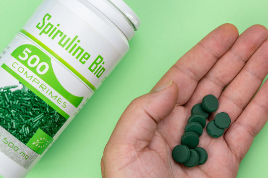 Closeup on box of organic spirulina in pills on green background