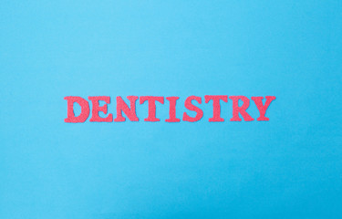 The word dentistry on a blue background. Concept sections of medicine dealing with dental treatment...