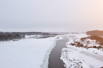 Winter nature, melted river through the snow. Cloudy winter day, background, copy space