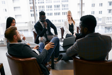 Fototapeta premium African american handsome businessman in tuxedo talking with business partners in office, telling how to be successful