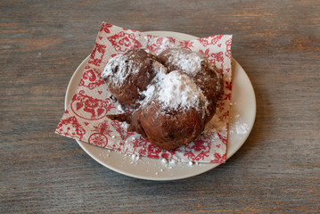 Typical Dutch new year's eve treat - tradictional oliebollen with powdered suger on white plate with napkin