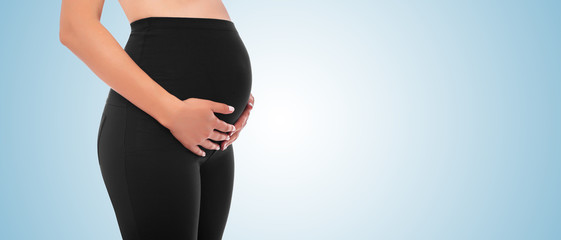 The body of a pregnant young woman on a blue background.