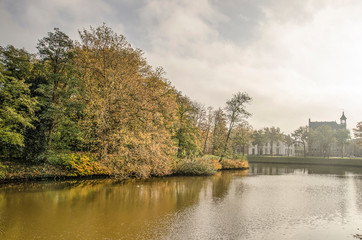 Fototapeta na wymiar Zwolle, the Netherlands, November 11, 2019: view across the town's ramparts canal towards the adjacent park on a somewhat misty day in autumn